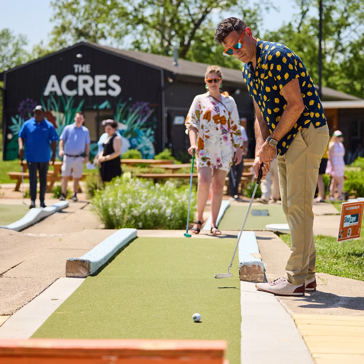 Guests playing mini golf in front of The Acres clubhouse